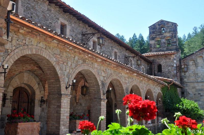 Castello Di Amorosa: каменные арки и красные герани в солнечном дворе